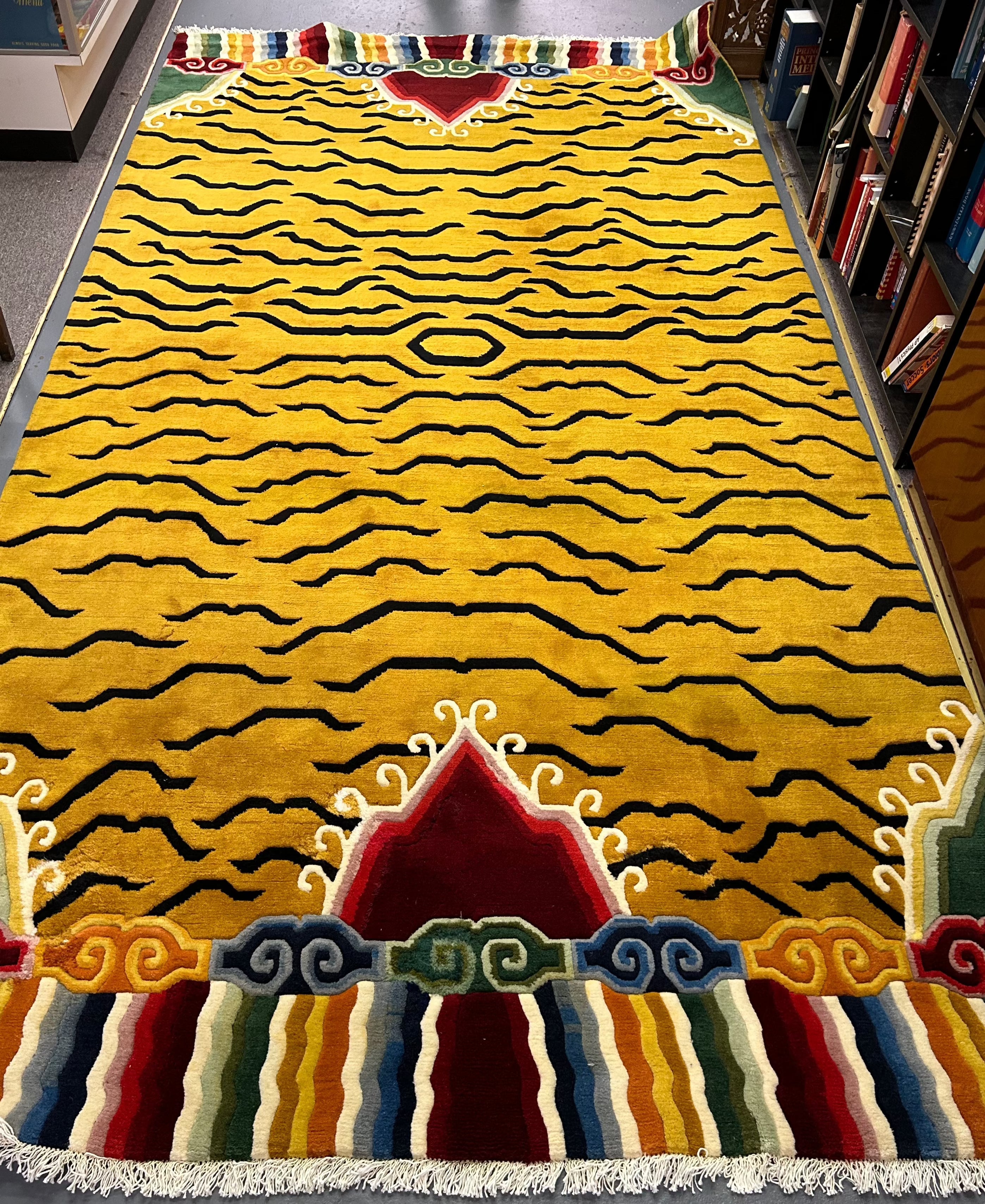 Handwoven Tibetan wool rug with a colorful mountain scene on either end of the rug with a semi flowing-geometric tiger inspired design in the middle.