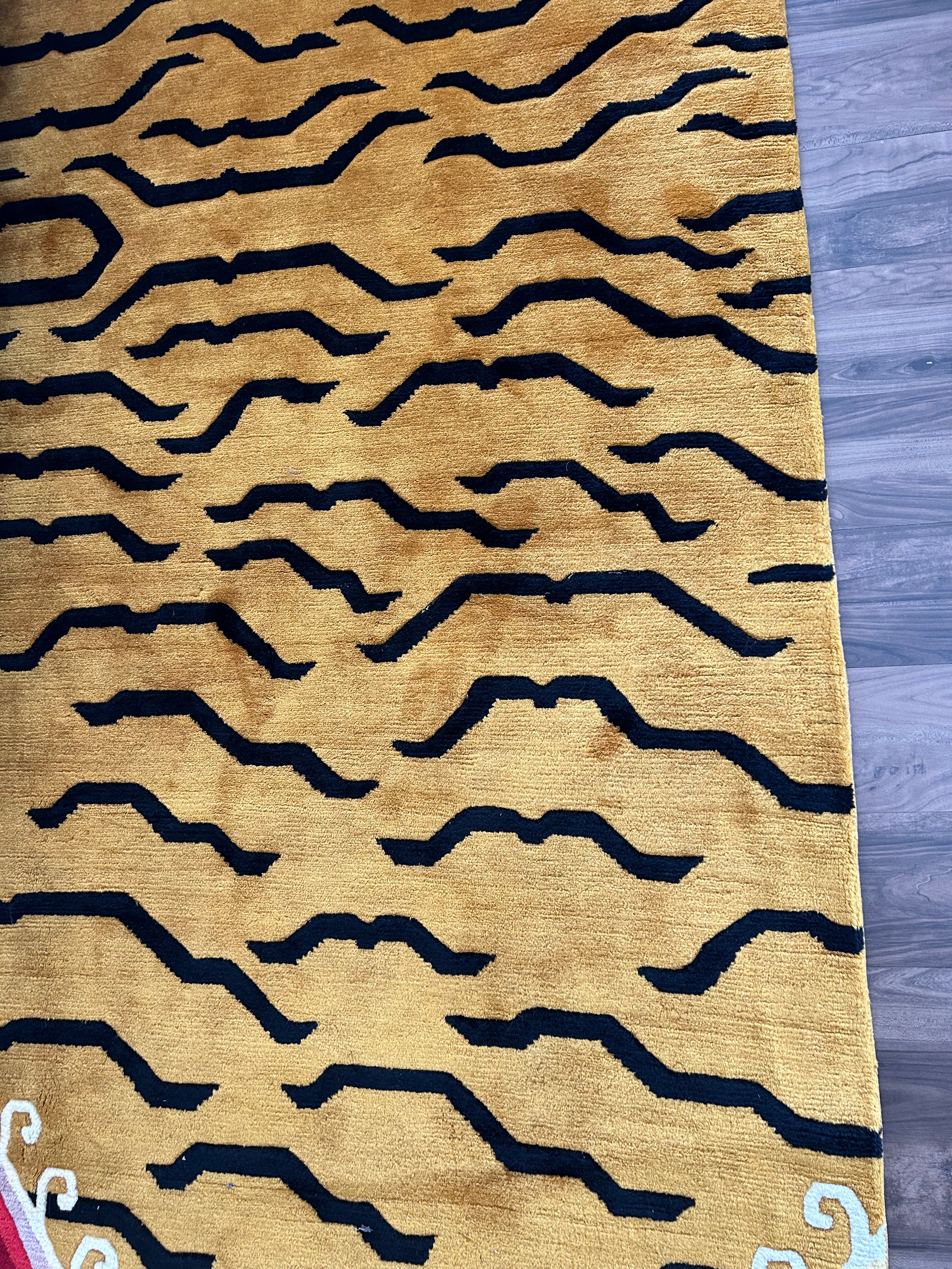 Handwoven Tibetan wool rug with a colorful mountain scene on either end of the rug with a semi flowing-geometric tiger inspired design in the middle.